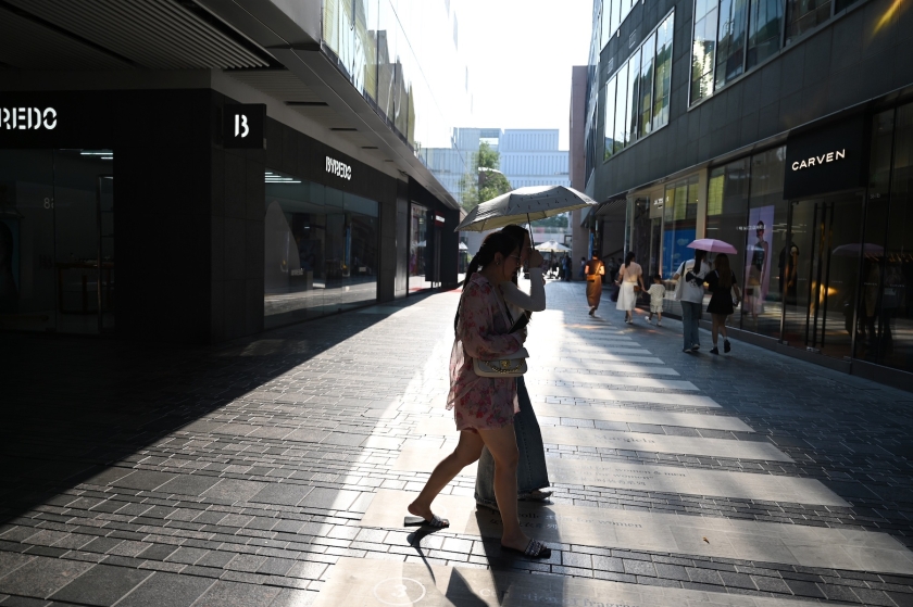 Uma mulher atravessa uma rua da cidade em meio às altas temperaturas