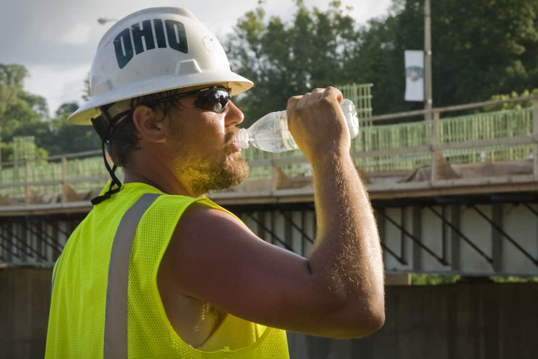 Um trabalhador da construção civil bebe de uma garrafa de água