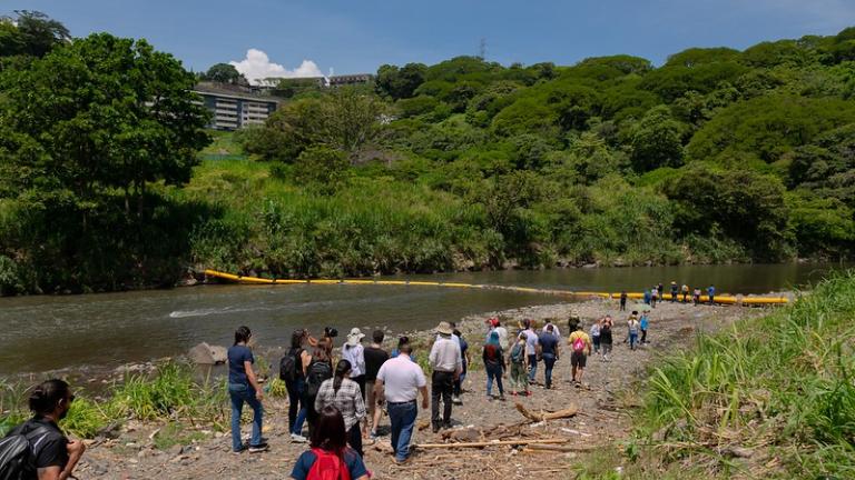 Os participantes da Costa Rica Academia da Cidade caminham pelas margens do Rio Virilla para ver a barreira de plástico que retém os resíduos.