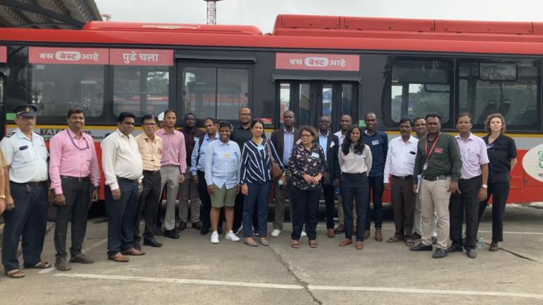 Os participantes do intercâmbio Peer to Peer do site UrbanShift em frente a um ônibus de emissão zero em Mumbai