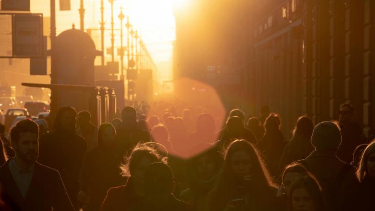 Pessoas caminhando em uma rua da cidade em direção ao sol