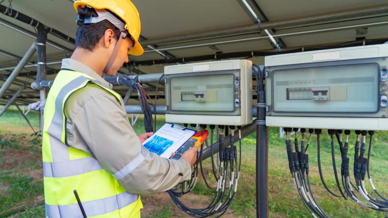 Homem verificando dados na parte traseira de uma usina de energia solar