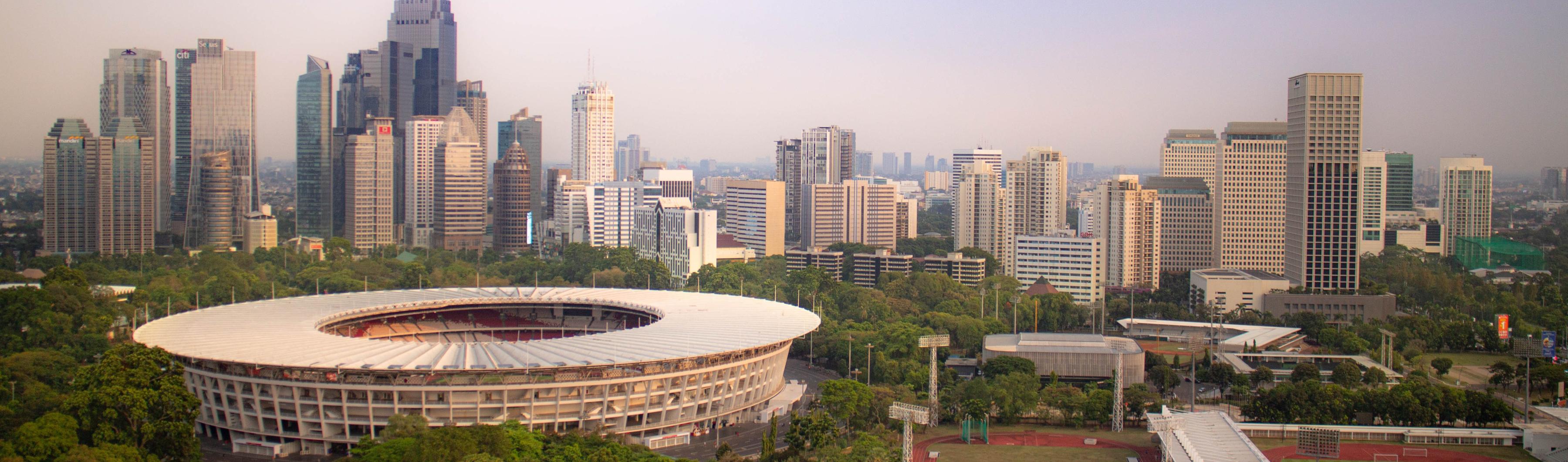 Vista do Estádio Gelora Bung Karno, em Jacarta, cercado por árvores e pelo horizonte da cidade